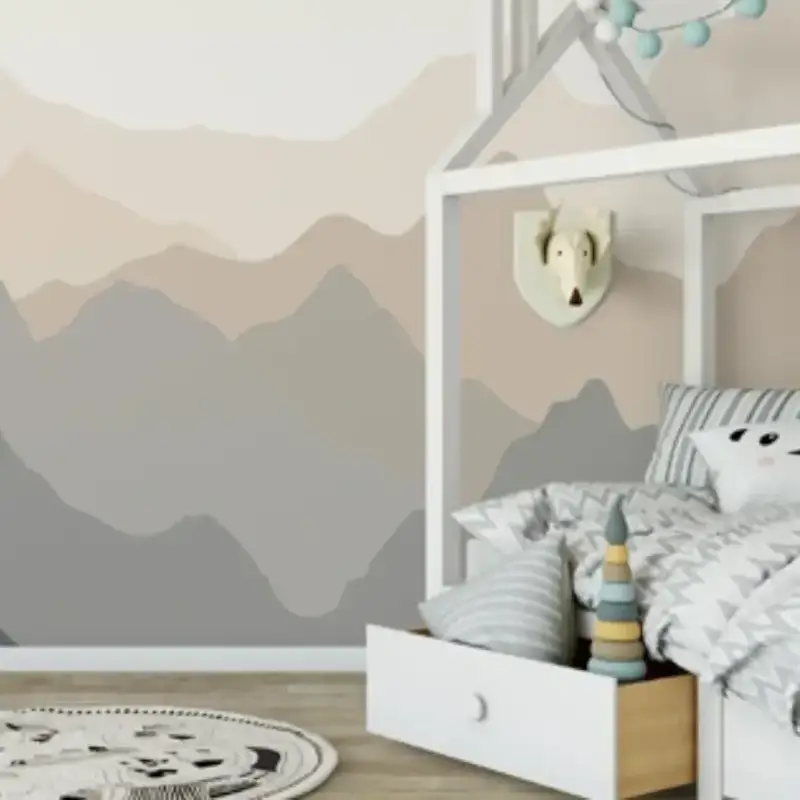 Children’s bedroom with a mountains mural printed by expert Printing Services, a white house-shaped bed frame, animal-themed pillows, pull-out drawer, round rug, and a decorative animal head on the wall.